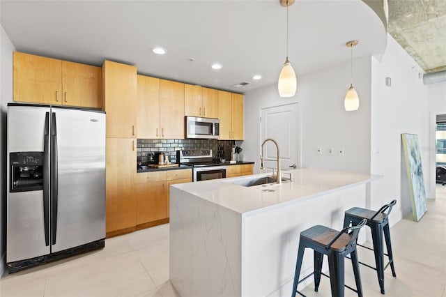 kitchen featuring hanging light fixtures, sink, decorative backsplash, an island with sink, and appliances with stainless steel finishes