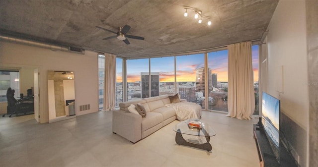 living room featuring ceiling fan, plenty of natural light, expansive windows, and concrete flooring