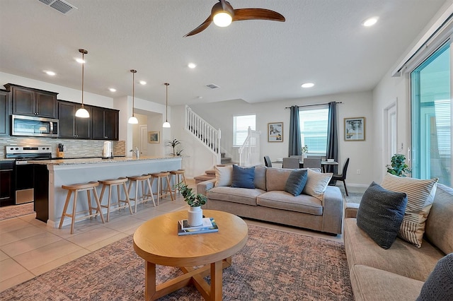 living room featuring light tile patterned floors, a textured ceiling, ceiling fan, and sink