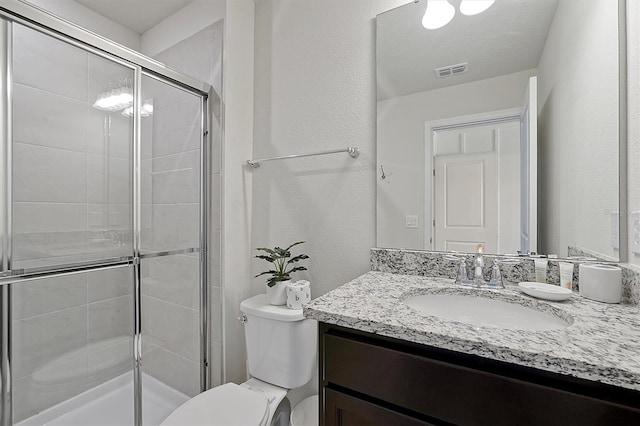 bathroom featuring a shower with door, vanity, and toilet