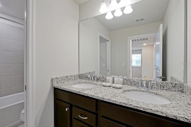 full bathroom featuring vanity, tiled shower / bath combo, and toilet