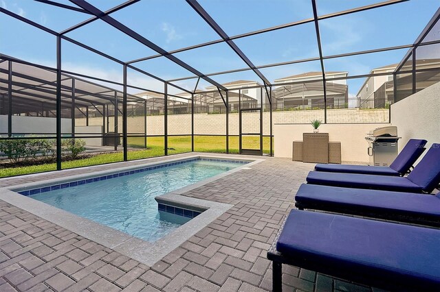 view of pool with a yard, glass enclosure, area for grilling, and a patio area