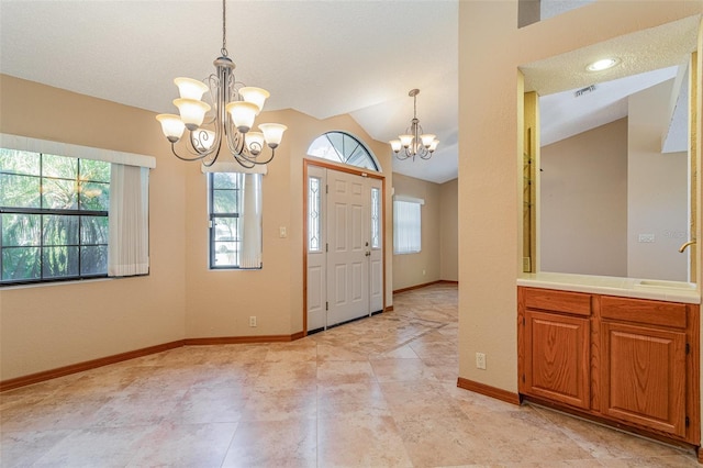 foyer entrance with vaulted ceiling, a notable chandelier, and sink