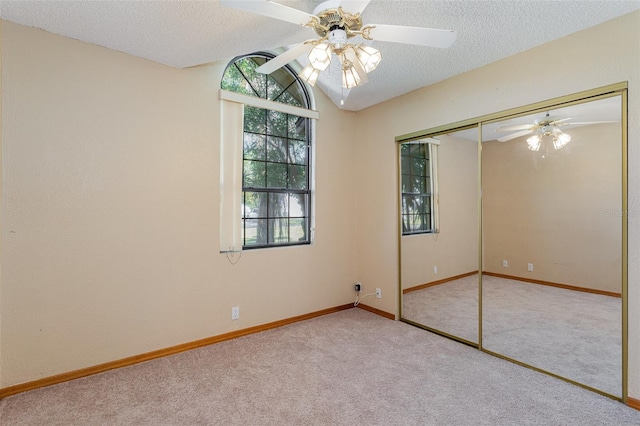 unfurnished bedroom with light carpet, a closet, ceiling fan, and lofted ceiling