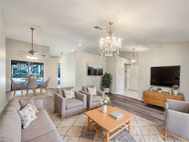 living room featuring ceiling fan with notable chandelier and light wood-type flooring