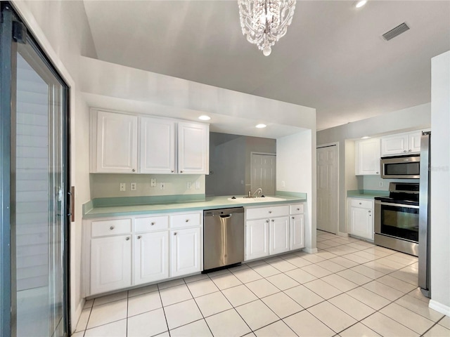 kitchen with sink, stainless steel appliances, an inviting chandelier, white cabinets, and light tile patterned flooring