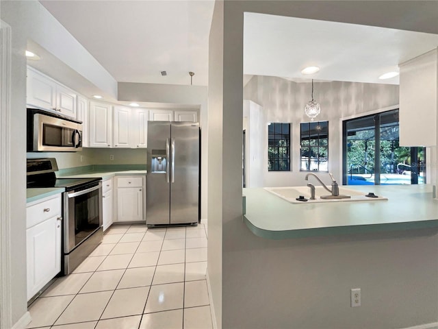 kitchen featuring kitchen peninsula, light tile patterned floors, appliances with stainless steel finishes, decorative light fixtures, and white cabinetry