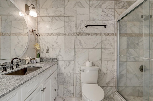 bathroom with vanity, toilet, a shower with door, and tile walls