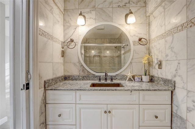 bathroom with vanity, an enclosed shower, and tile walls