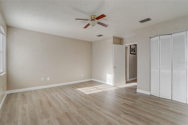 unfurnished bedroom with a textured ceiling, a closet, light hardwood / wood-style floors, and ceiling fan