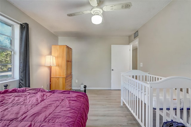 bedroom featuring ceiling fan, baseboards, visible vents, and light wood-type flooring