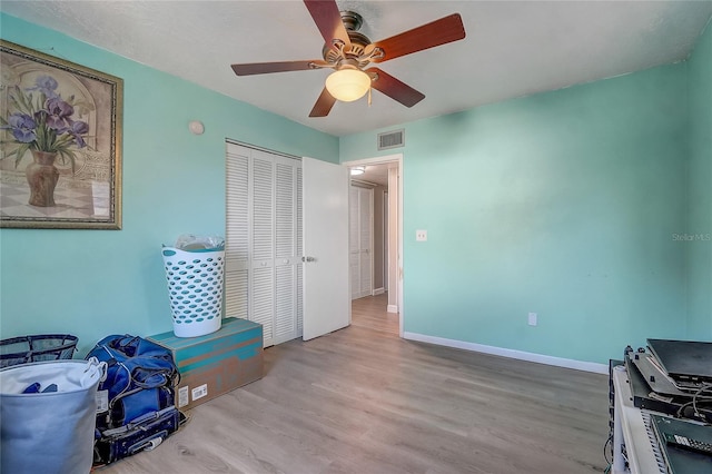 bedroom featuring baseboards, visible vents, a ceiling fan, wood finished floors, and a closet