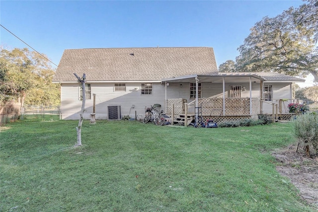 back of house with roof with shingles, fence, and a yard