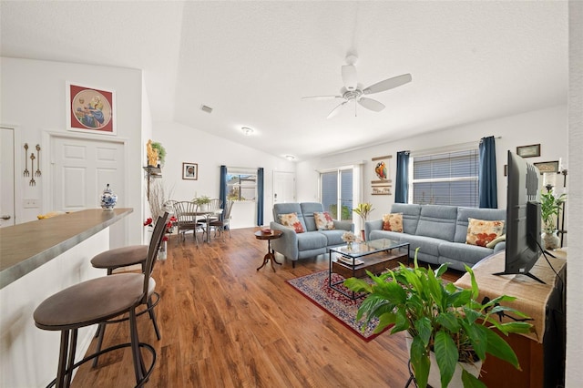 living room with hardwood / wood-style floors, ceiling fan, and vaulted ceiling