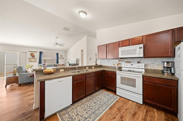 kitchen featuring white appliances, sink, vaulted ceiling, light wood-type flooring, and kitchen peninsula