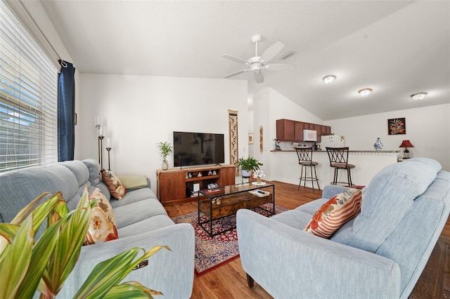 living room with hardwood / wood-style floors, ceiling fan, and lofted ceiling