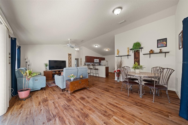 living room with wood-type flooring, vaulted ceiling, and ceiling fan