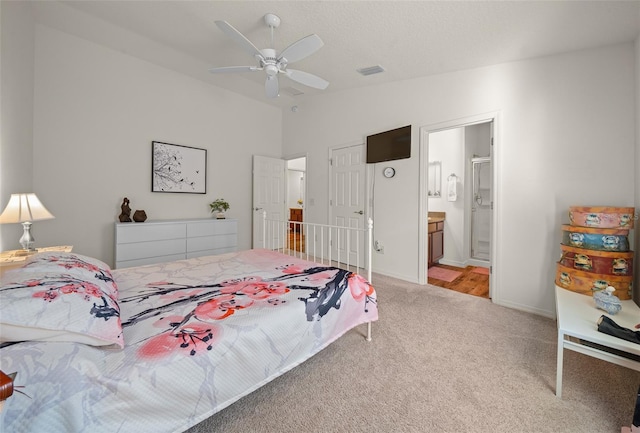 bedroom with ensuite bath, ceiling fan, light colored carpet, and lofted ceiling