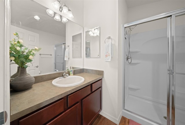 bathroom with wood-type flooring, vanity, and an enclosed shower