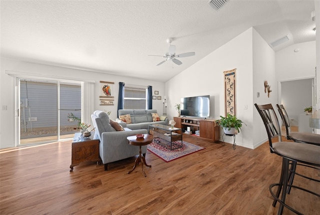 living room with hardwood / wood-style floors, ceiling fan, a textured ceiling, and high vaulted ceiling