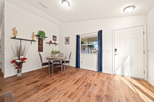 foyer entrance featuring lofted ceiling, wood-type flooring, and a textured ceiling