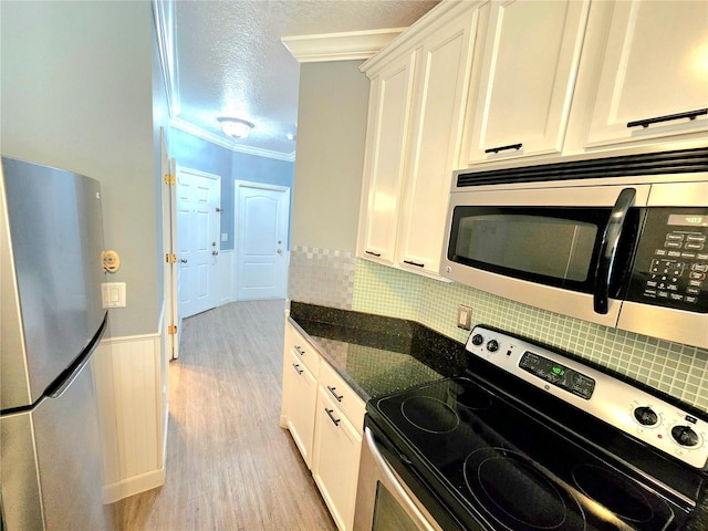 kitchen with appliances with stainless steel finishes, tasteful backsplash, white cabinetry, and crown molding