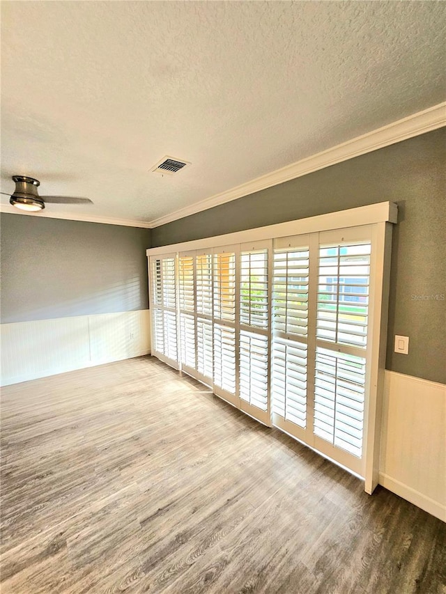 spare room with hardwood / wood-style flooring, plenty of natural light, ceiling fan, and a textured ceiling