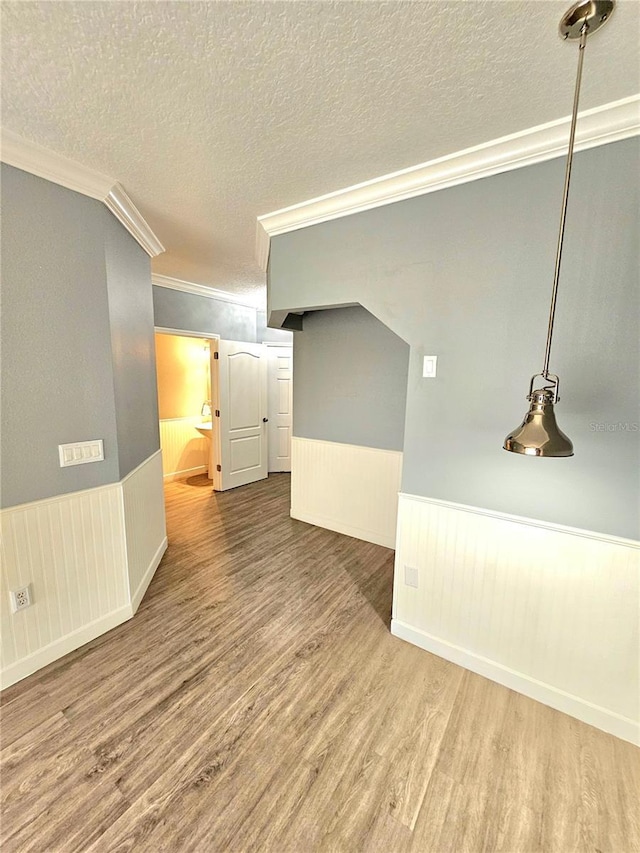 empty room featuring wood-type flooring, a textured ceiling, and ornamental molding