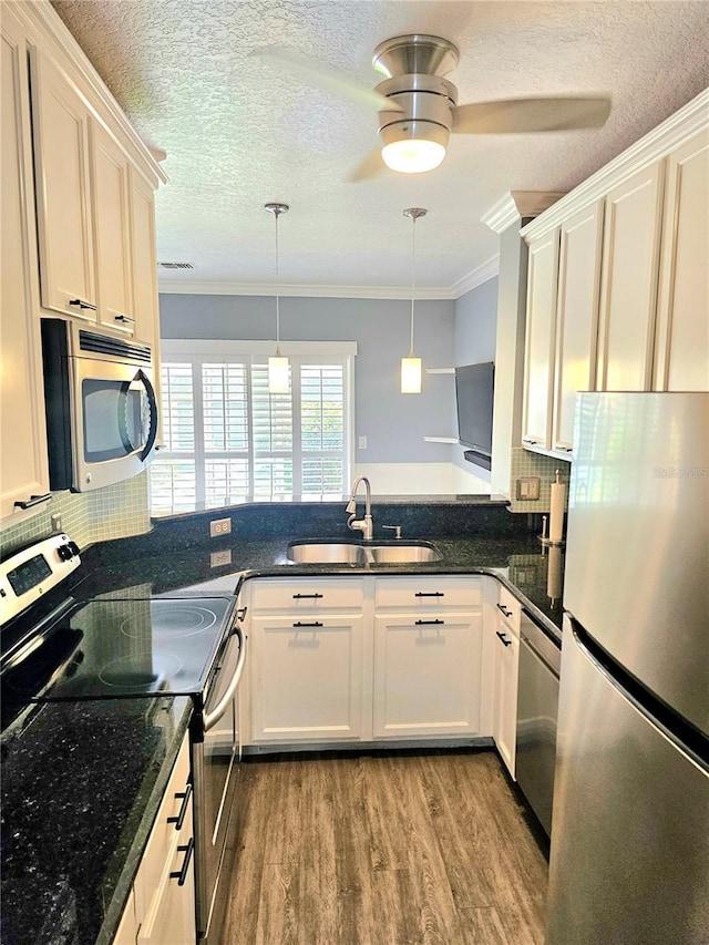 kitchen with sink, crown molding, decorative light fixtures, light hardwood / wood-style floors, and stainless steel appliances