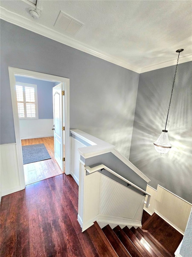 staircase with hardwood / wood-style floors, a textured ceiling, and crown molding