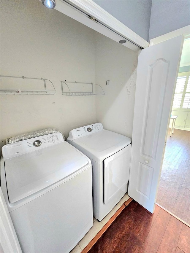 clothes washing area featuring washer and clothes dryer and hardwood / wood-style flooring