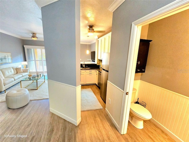 interior space with crown molding, sink, light hardwood / wood-style floors, and a textured ceiling