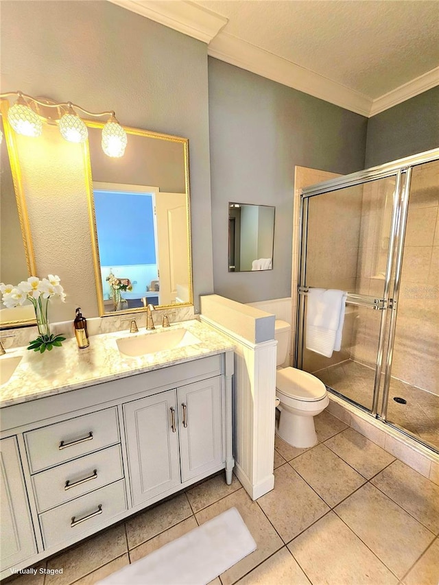 bathroom featuring vanity, a shower with door, tile patterned floors, crown molding, and toilet