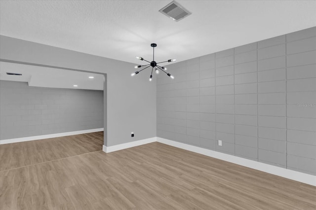 interior space featuring light hardwood / wood-style floors, a textured ceiling, and a notable chandelier