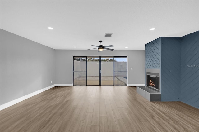 unfurnished living room with a fireplace, wood-type flooring, and ceiling fan