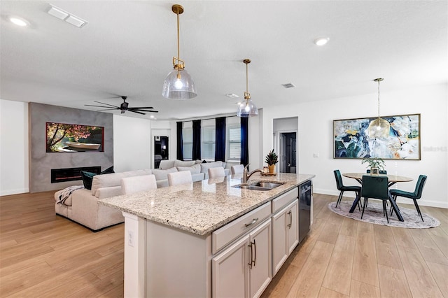 kitchen featuring decorative light fixtures, a kitchen island with sink, and light hardwood / wood-style flooring