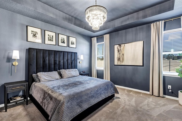 bedroom with carpet flooring, a tray ceiling, an inviting chandelier, and multiple windows