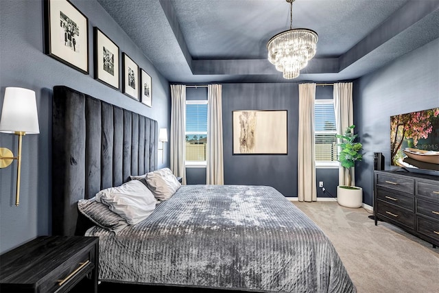 carpeted bedroom with a tray ceiling, an inviting chandelier, and multiple windows