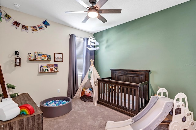 bedroom with carpet flooring, ceiling fan, and a crib