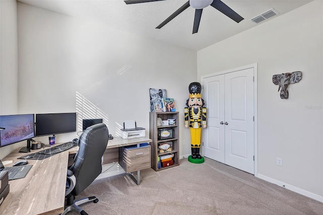 home office with a textured ceiling, ceiling fan, and light carpet