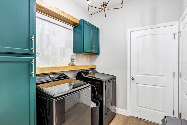 laundry area with washer and clothes dryer, cabinets, a notable chandelier, and light wood-type flooring