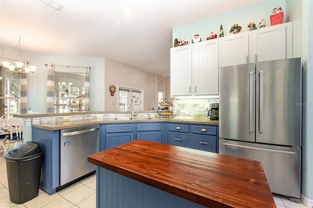 kitchen featuring white cabinets, appliances with stainless steel finishes, an inviting chandelier, and blue cabinets