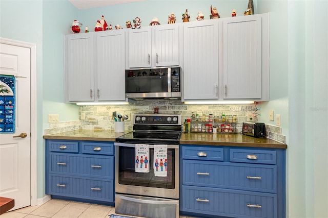 kitchen with light tile patterned floors, blue cabinetry, appliances with stainless steel finishes, tasteful backsplash, and white cabinetry