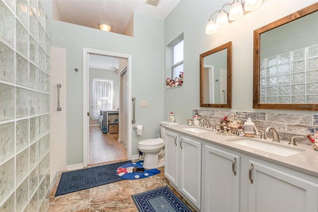 bathroom with decorative backsplash, walk in shower, vanity, wood-type flooring, and toilet