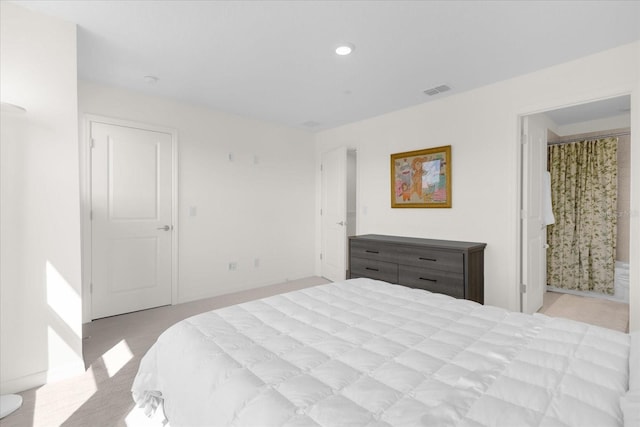 bedroom with light carpet and connected bathroom