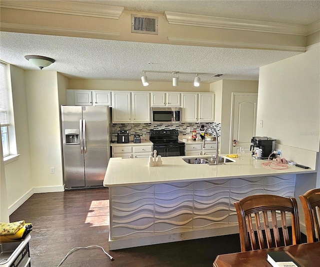 kitchen featuring kitchen peninsula, stainless steel appliances, sink, dark hardwood / wood-style floors, and white cabinetry