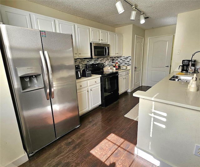 kitchen with tasteful backsplash, stainless steel appliances, white cabinetry, and dark hardwood / wood-style floors