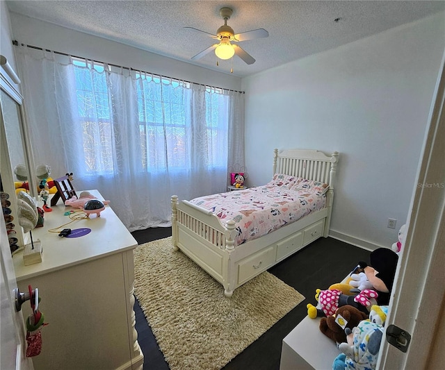 bedroom with ceiling fan, dark hardwood / wood-style floors, and a textured ceiling