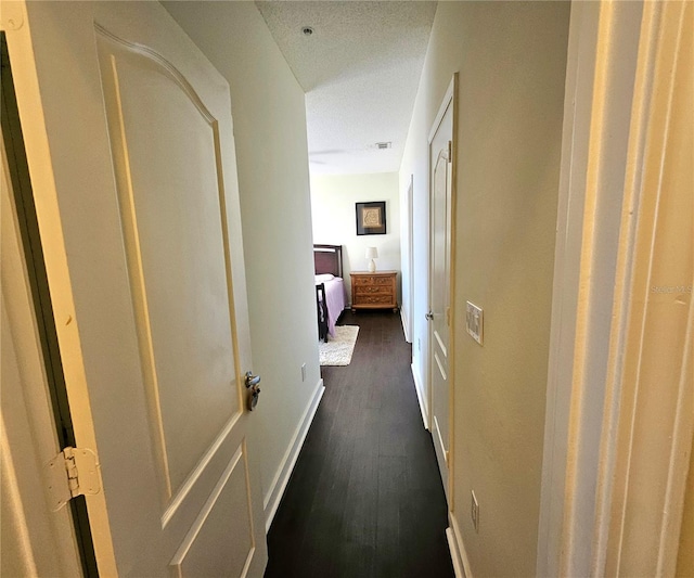 hallway with dark hardwood / wood-style flooring and a textured ceiling