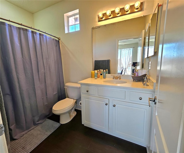 bathroom with a shower with shower curtain, vanity, toilet, and a healthy amount of sunlight